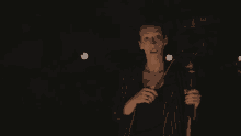 a woman is holding a microphone and giving a thumbs up sign in the dark .