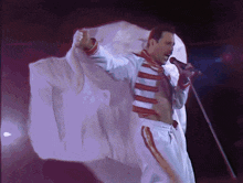 a man singing into a microphone with a white cloth covering his arms