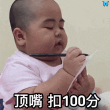 a baby is holding a pen and a piece of paper and says 100