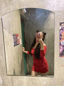 a woman in a red dress takes a selfie in a mirror