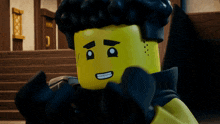 a close up of a yellow lego figure with black hair and a black scarf around his neck