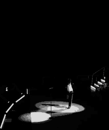 a man singing into a microphone on a stage with stairs in the background
