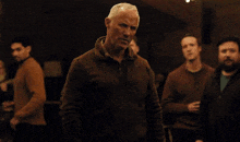 a group of men are dancing in a room with christmas lights in the background .