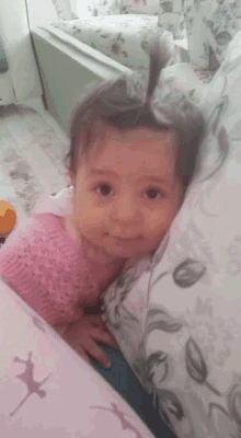 a baby girl in a pink dress is laying on a pillow