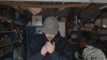 a man smoking a cigarette in a garage while wearing a hat with the letter g on it