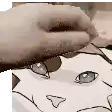 a close up of a person 's hand holding a piece of paper with a cat on it .