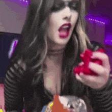 a woman in a black and white striped shirt is holding a red gummy bear .
