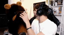 a man wearing headphones holds a stuffed bear