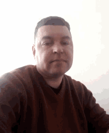 a man in a brown sweater is taking a selfie with his face visible .