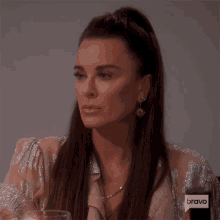a woman sitting at a table with a bravo logo on the bottom