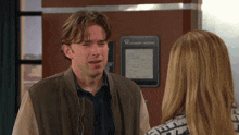 a man and a woman are talking in front of a sign that says ' varsity hospital '
