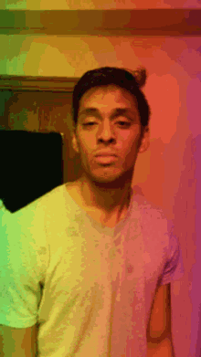 a man in a white t-shirt stands in front of a rainbow wall