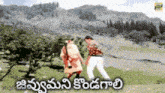 a man and a woman are dancing in a field with mountains in the background and the words in telugu