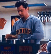 a man in a bruins sweatshirt is cooking in a kitchen