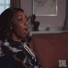 a woman sitting on a couch with snl written on the back