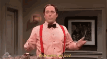 a man in a pink shirt and red suspenders is standing in front of a table and saying `` dick move , my bad '' .