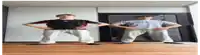 two dolls are standing next to each other on a wooden floor .