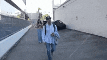 a man and a woman are walking down a sidewalk next to a parking lot .