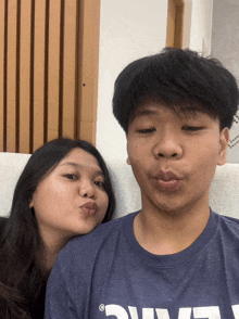 a boy wearing a blue shirt with the letter l on it kisses a girl