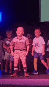a group of young boys are standing on a stage and one of them is wearing a shirt with a peace sign on it