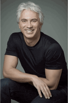 a man with gray hair and a black shirt smiles