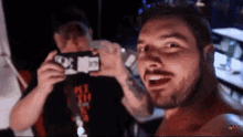 a man with a beard is taking a picture of another man with a cell phone