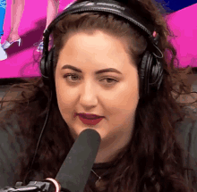 a woman wearing headphones and a microphone with a pink background