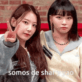 two girls are standing next to each other and one is giving a peace sign .