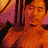 a shirtless man with a beard looks down at something