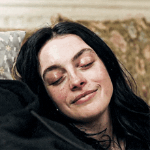 a woman laying on a couch with her eyes closed and a smile on her face