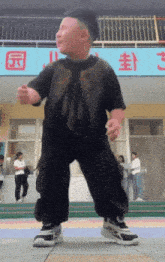 a little boy is dancing in front of a sign that says ' s ' on it