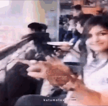 a woman is holding a hamburger in front of a crowd of people in a restaurant .