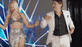 a man in a white suit and a woman in a silver dress are dancing together