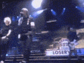 a band is playing on a stage with a sign that says loser
