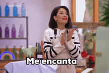 a woman in a striped sweater applauds with the words me encanta below her