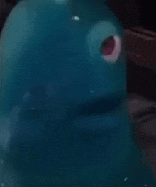a close up of a blue cartoon character with red eyes