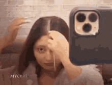 a woman is taking a picture of herself in front of a cell phone .