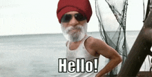 a man with a beard wearing a red hat and sunglasses is standing on a beach .