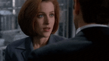 a man in a suit and tie looks at a woman in a white shirt