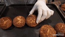 a person is cutting a cookie on a tray that says made in animatica on the bottom