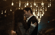 a man and a woman are touching their noses in front of a fireplace