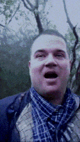 a man with his mouth open wearing a plaid shirt and a blue jacket