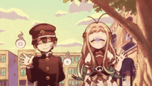 a boy and a girl are standing next to each other in front of a tree in a city .