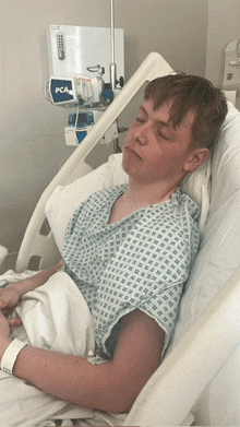 a man in a hospital gown is laying in a hospital bed next to a box that says pca