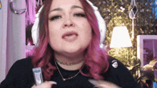 a woman with pink hair is wearing white headphones and a choker