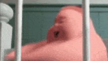 a pink baby is sleeping in a crib behind a white fence .