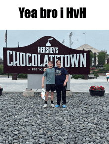 two men standing in front of a hershey 's chocolatetown sign