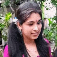 a close up of a woman 's face with pigtails and a bindi on her forehead .