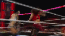 two women are wrestling in a wrestling ring and one of them is wearing a red top