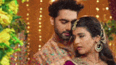 a man and a woman are standing next to each other in front of flowers and lights .